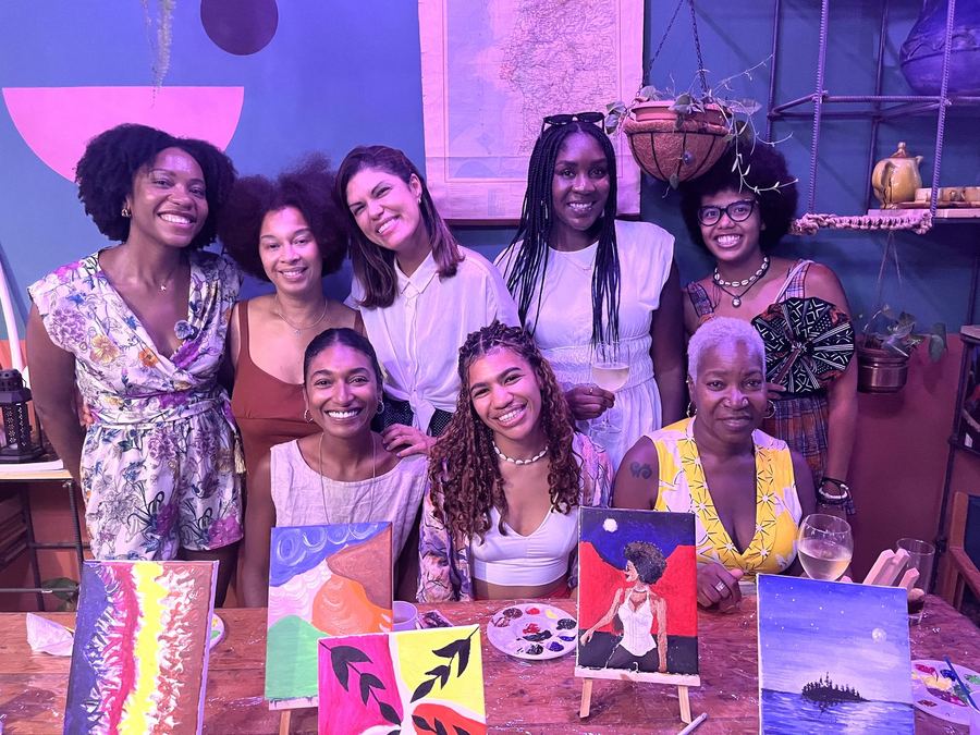 Members smiling together behind their paintings at a creative workshop